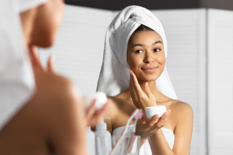 Afro Young Lady Applying Face Cream Standing In Bathroom Panorama